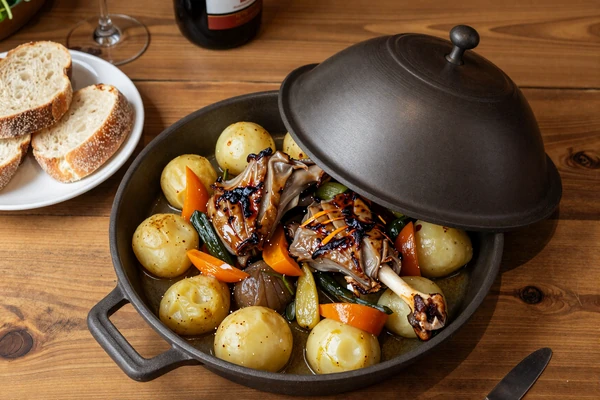 Traditional Croatian peka dish with roasted lamb and vegetables on rustic table - authentic Croatian cuisine for dating experience